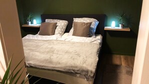 A neatly made bed with a star-patterned bedspread, two pillows, and a headboard. There are two bedside tables with lamps and potted plants. - Centrally located for Harz visitors, fair guests, fitters, Alfeld (5min), Leineberg (Alfeld (Leine))