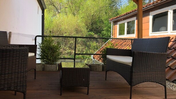 A covered outdoor area with wicker furniture and a view of trees and a building. - Centrally located for Harz visitors, fair guests, fitters, Alfeld (5min), Leineberg (Alfeld (Leine))
