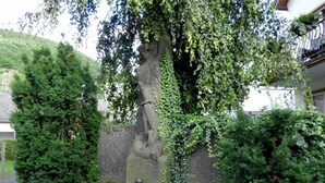A cemetery with a large tree, a stone wall, and a flower bed. - Relax in the old Winzerhaus holiday house (Rech)