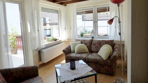 A cozy living room with a floral sofa, a coffee table, and a floor lamp. - Relax in the old Winzerhaus holiday house (Rech)