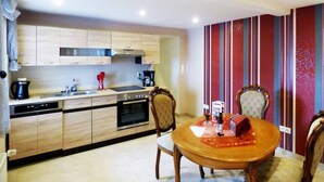 A modern kitchen with wooden cabinets, a dining table with chairs, and a striped wall. - Relax in the old Winzerhaus holiday house (Rech)