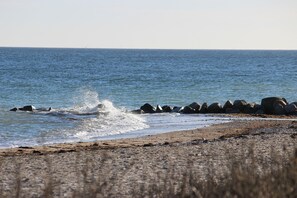 Une plage où les vagues s’écrasent contre les rochers, offrant une vue dégagée sur l’océan.
