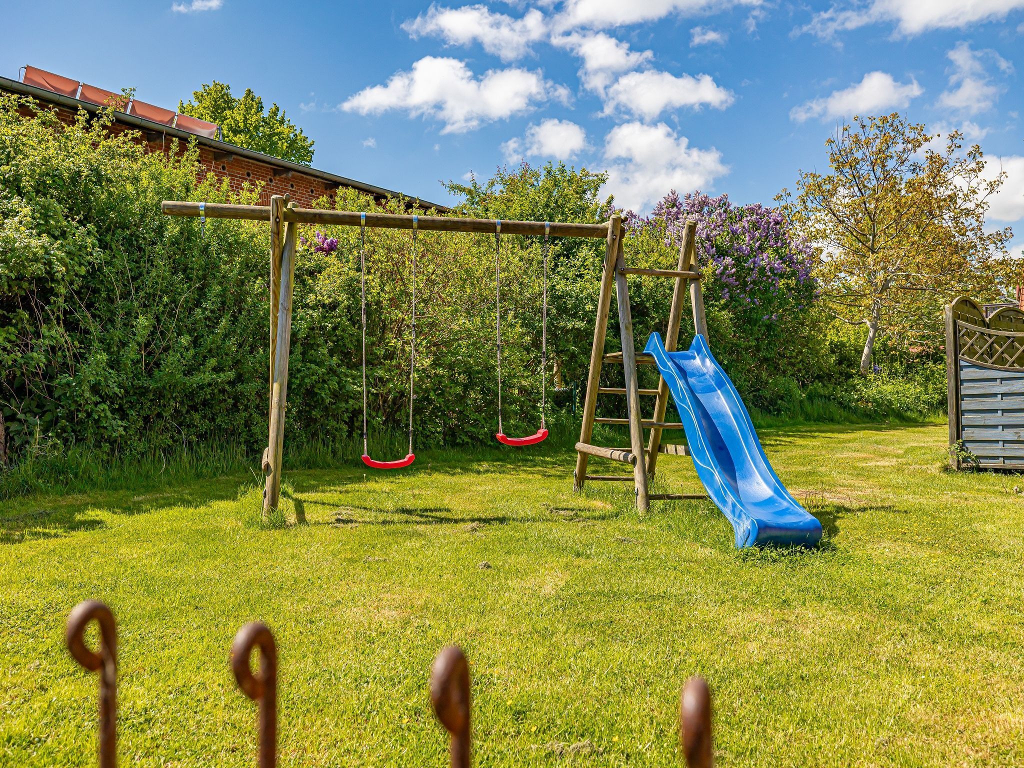 A playground with swings and a slide in a grassy yard.