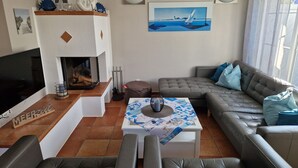 Een woonkamer met een open haard, een televisie, een bank en een schilderij van een zeilboot.
