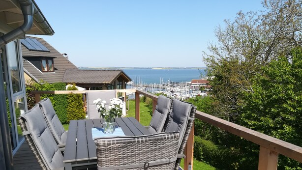 A deck with a table and chairs, overlooking a marina and the sea. - Fantastic, sunny apartment with Baltic Sea view and balcony near the beach (Langballigholz)