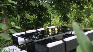 An outdoor dining area with a glass-top table and wicker chairs.
