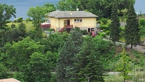 Una casa de una planta con puerta principal roja, un pequeño porche y vista al lago.