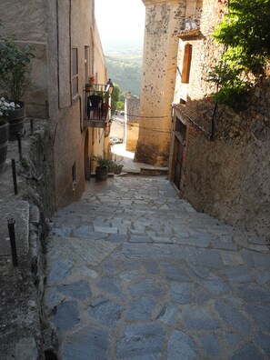 A narrow stone-paved alleyway flanked by buildings with balconies and potted plants. - Maissonette with light, great room layout, ideal for remote working GLASFASER (Torroja del Priorat)