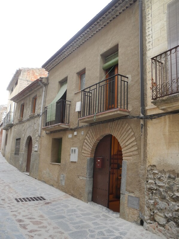 A narrow street with historic buildings featuring stone facades, arched doorways, and balconies with metal railings. - Maissonette with light, great room layout, ideal for remote working GLASFASER (Torroja del Priorat)