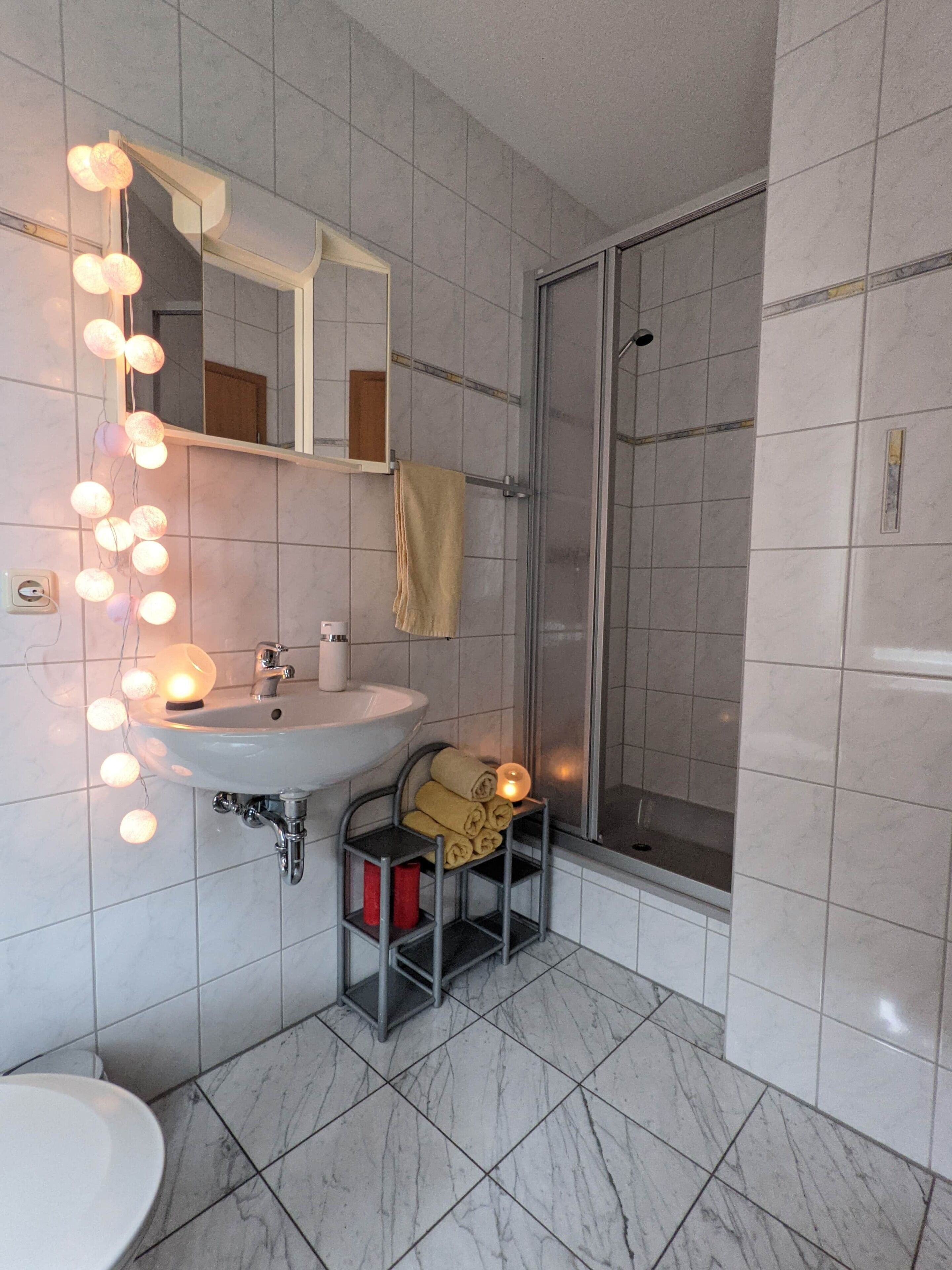 Ein Badezimmer mit Waschbecken, Spiegel, Handtuchhalter und Dusche.