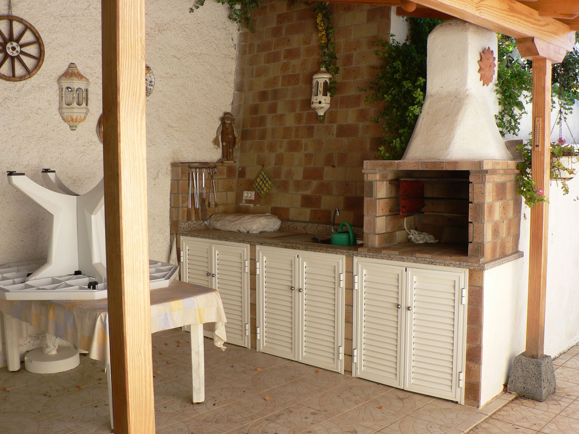 Une cuisine extérieure en briques, dotée d’un four à pizza, d’une table et de chaises.