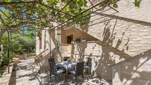 An outdoor patio with a table and chairs, surrounded by stone walls and greenery. - Two bedrooms Apartment Eva with beautiful garden in Funtana (Funtana)