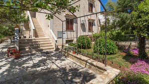 A stone staircase leading to a white building with a garden and a pergola structure. - Two bedrooms Apartment Eva with beautiful garden in Funtana (Funtana)