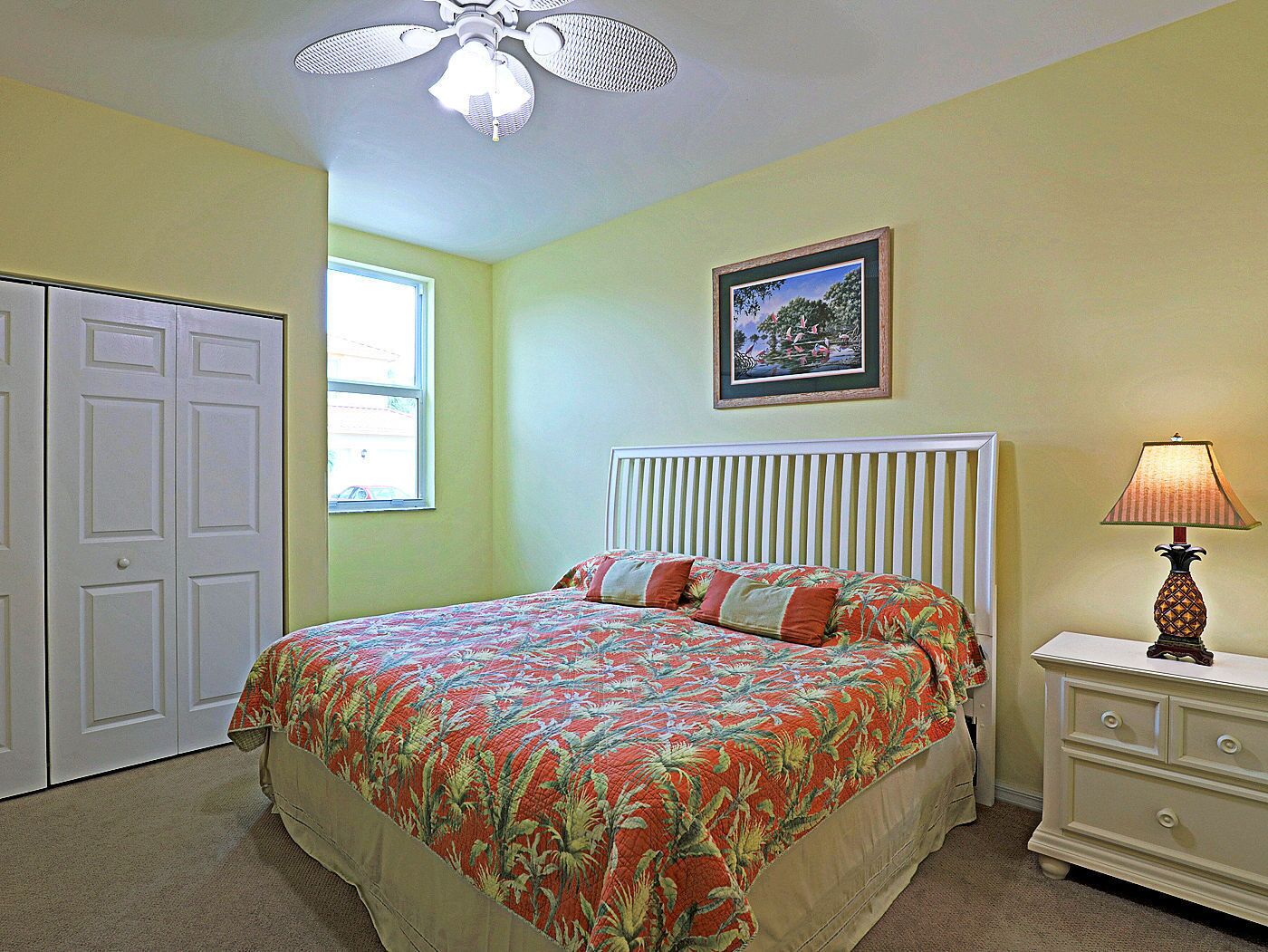 A bedroom with a bed, a nightstand, a lamp, a window, and a door.