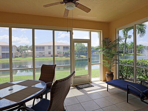 A room with a glass door leading to a pool, wicker furniture, and a ceiling fan.