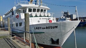 Un barco blanco llamado "Lady von Büsum" amarrado a un muelle.