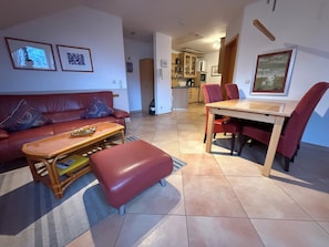 A living room with a sofa, a coffee table, and a dining table with chairs. There is a kitchen area in the background. - Family-friendly comfort apartment, 100m to the Baltic Sea beach, beautiful lagoon view (Rerik)