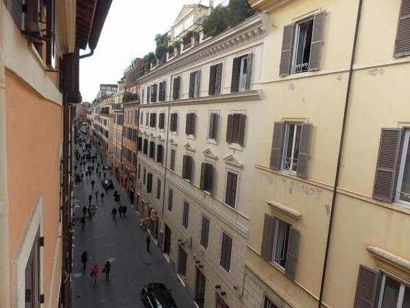 A narrow street lined with multi-story buildings, featuring balconies and shutters.