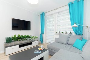 Relax in this stylish living room with a flat-screen TV, coffee table, and comfortable sofa, offering a view of the outdoors.