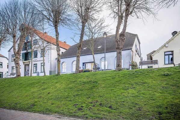 A building with a sloped roof, a sign reading "Silfhafenmuseum," and a grassy hill in the foreground.