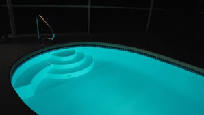 A swimming pool with a lighted edge and a single ladder. - Top location, heated privat pool, Wi-Fi, Tropical Garden, Child- and petfriendly (Cape Coral)