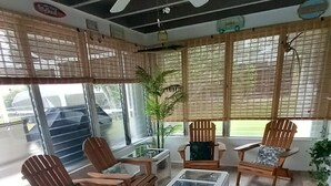 A sunlit room with wooden flooring, a ceiling fan, and a glass coffee table. - Top location, heated privat pool, Wi-Fi, Tropical Garden, Child- and petfriendly (Cape Coral)