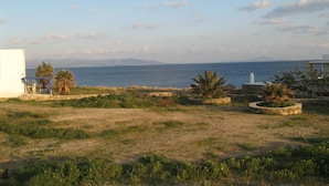 A coastal landscape with a view of the sea, a white building, and some greenery.