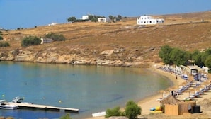A coastal area with a beach, boats, and a row of beach huts.
