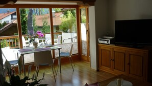 Uma sala de estar aconchegante com área de jantar, televisão e vista para o exterior.