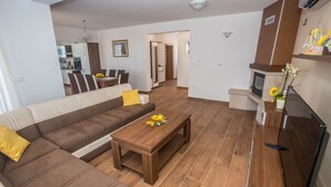 Een moderne woonkamer met een bruine modulaire bank, een houten salontafel en een keuken op de achtergrond.