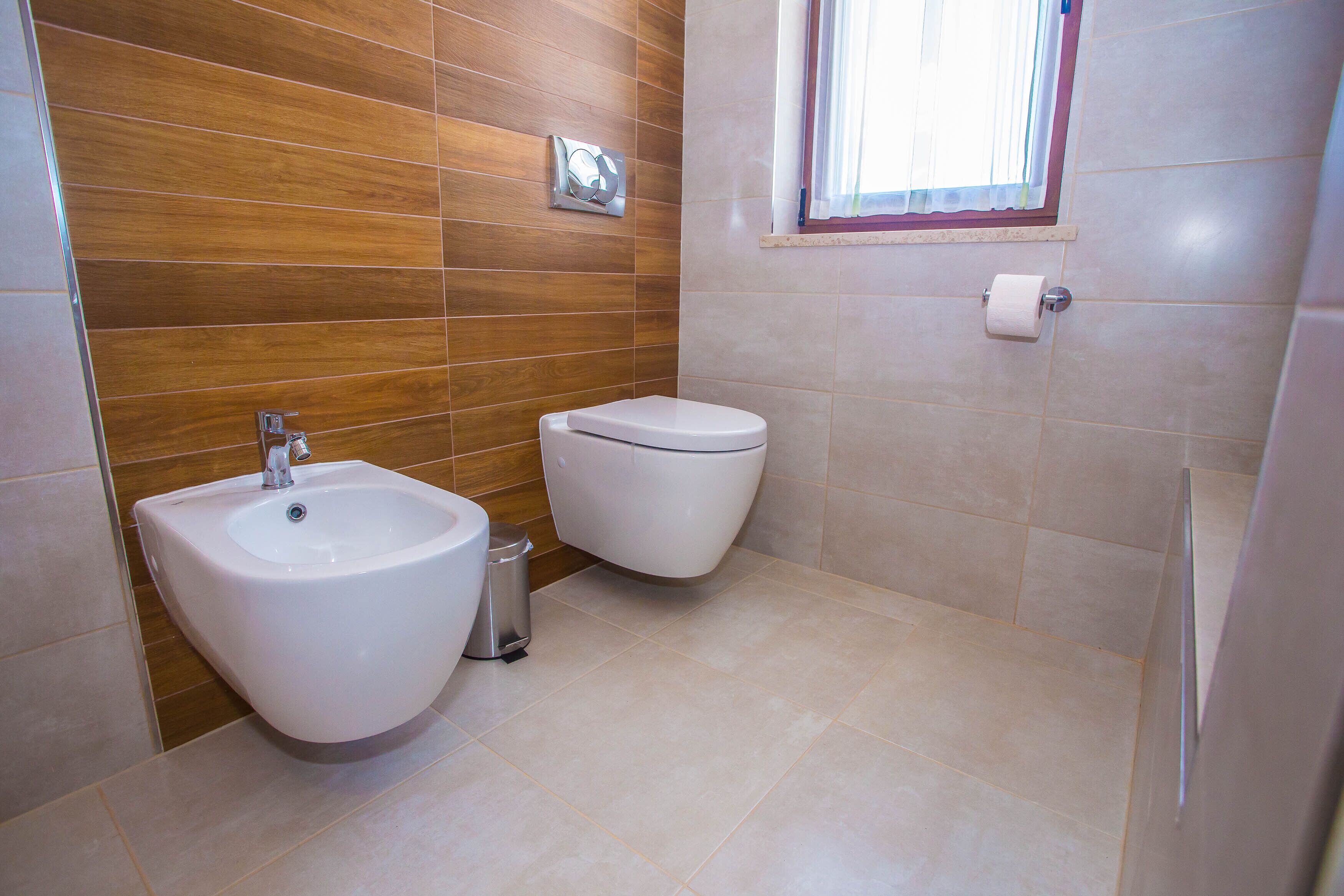 A bathroom with a bidet, toilet, and sink.