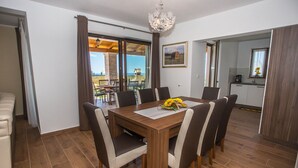 Een eetruimte met een houten tafel, zes stoelen en een kroonluchter.