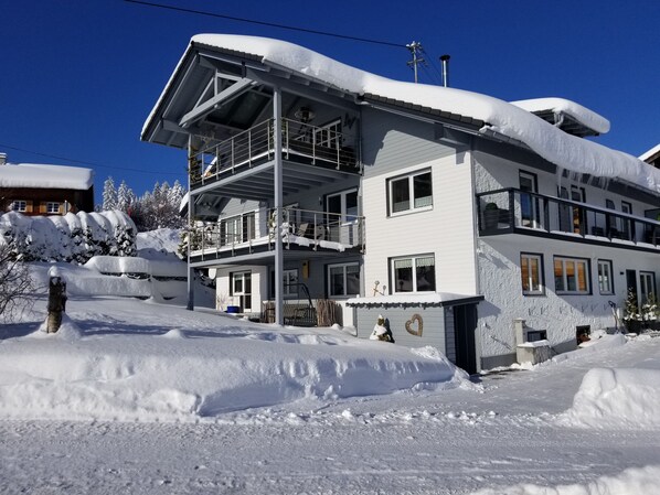 A multi-story building with balconies, surrounded by snow.
