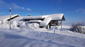 Un edificio cubierto de nieve con un estilo arquitectónico moderno, que presenta un balcón grande y varias ventanas.