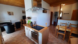 Eine kleine Küche mit Herd, Backofen und einer Essecke mit Tisch und Stühlen.