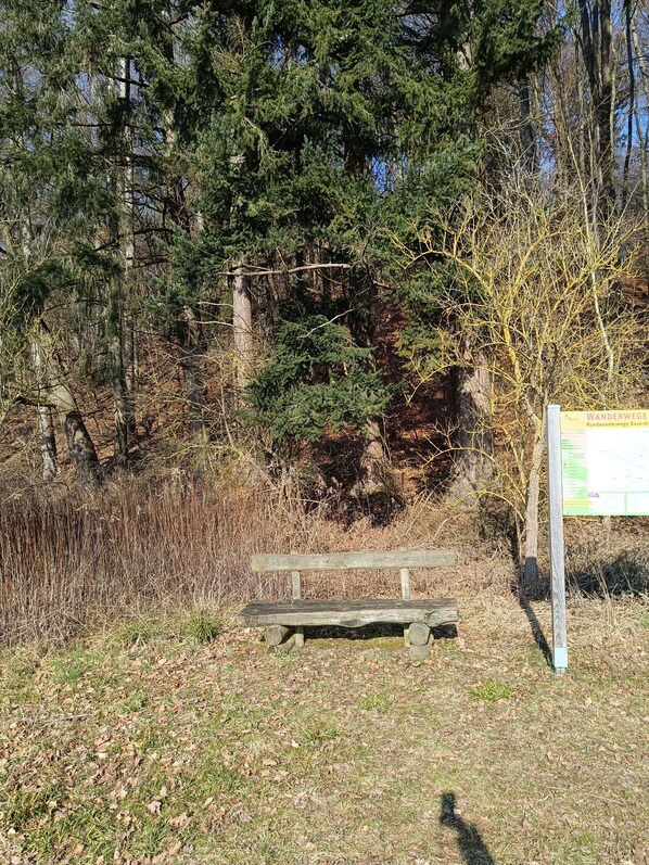 A wooden bench in a natural setting with a signboard nearby. - Vacation apartment between Lech and Danube-"Dorfliebe Reicherstein" (Pöttmes)