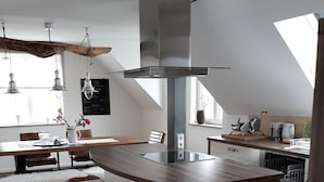 Eine moderne Küche mit einer zentralen Kochinsel, Holzböden, Pendelleuchten und einem großen Fenster.