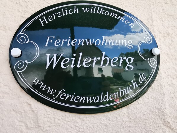 A welcome sign for a guesthouse named 'Ferienwohnung Weilerberg' with a website address. - Beautiful large apartment near Messe Stuttgart - Sindelfingen - Fildern (Waldenbuch)