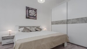 A modern bedroom with a bed, two bedside tables, a nightstand, a wall-mounted artwork, and a wardrobe. - Brand new and charming apartment Edi Blue with small garden in Funtana (Funtana)