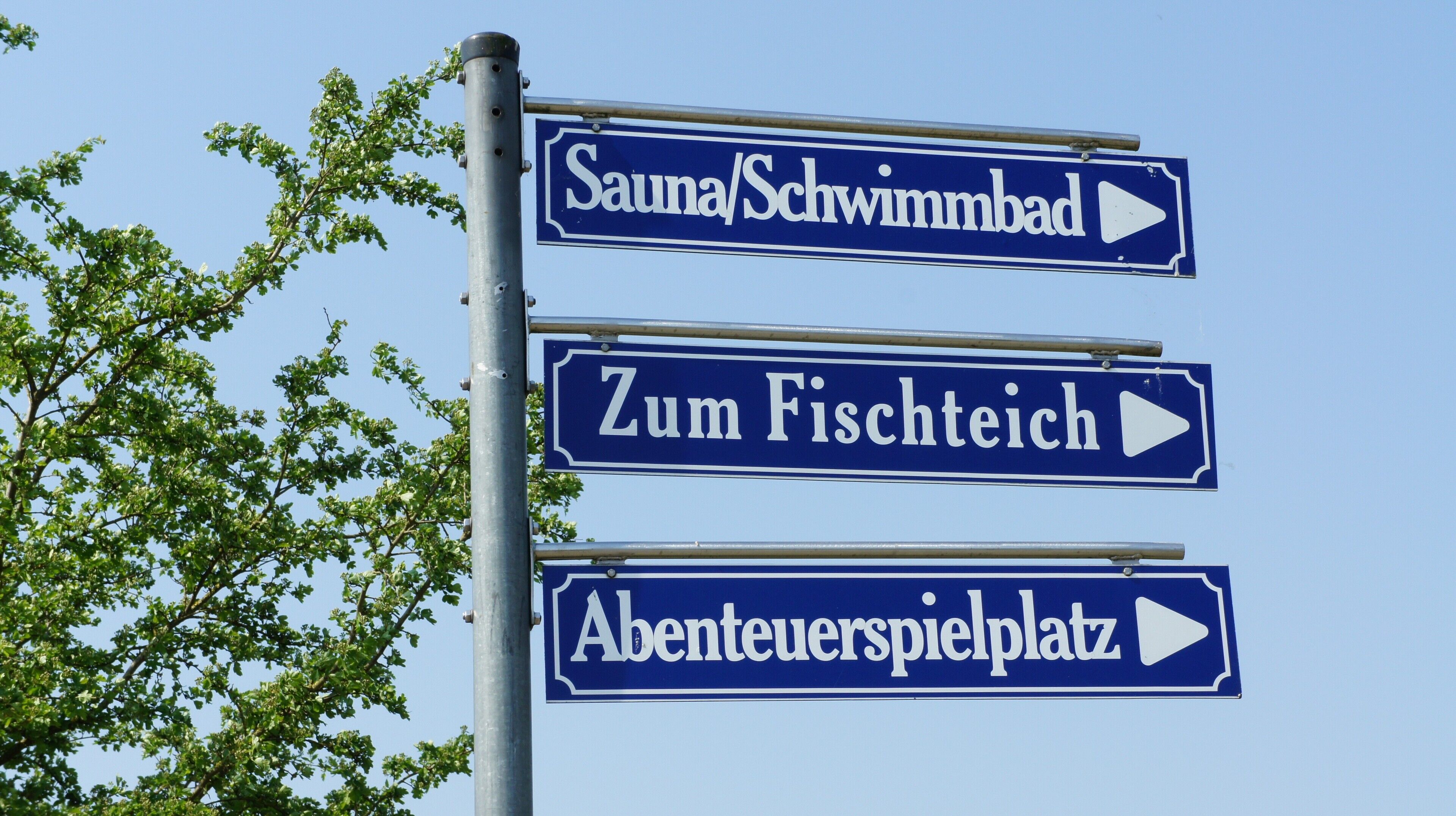 Directional signs for Sauna/Schwimmbad, Zum Fischeich, and Abenteuerspielplatz.