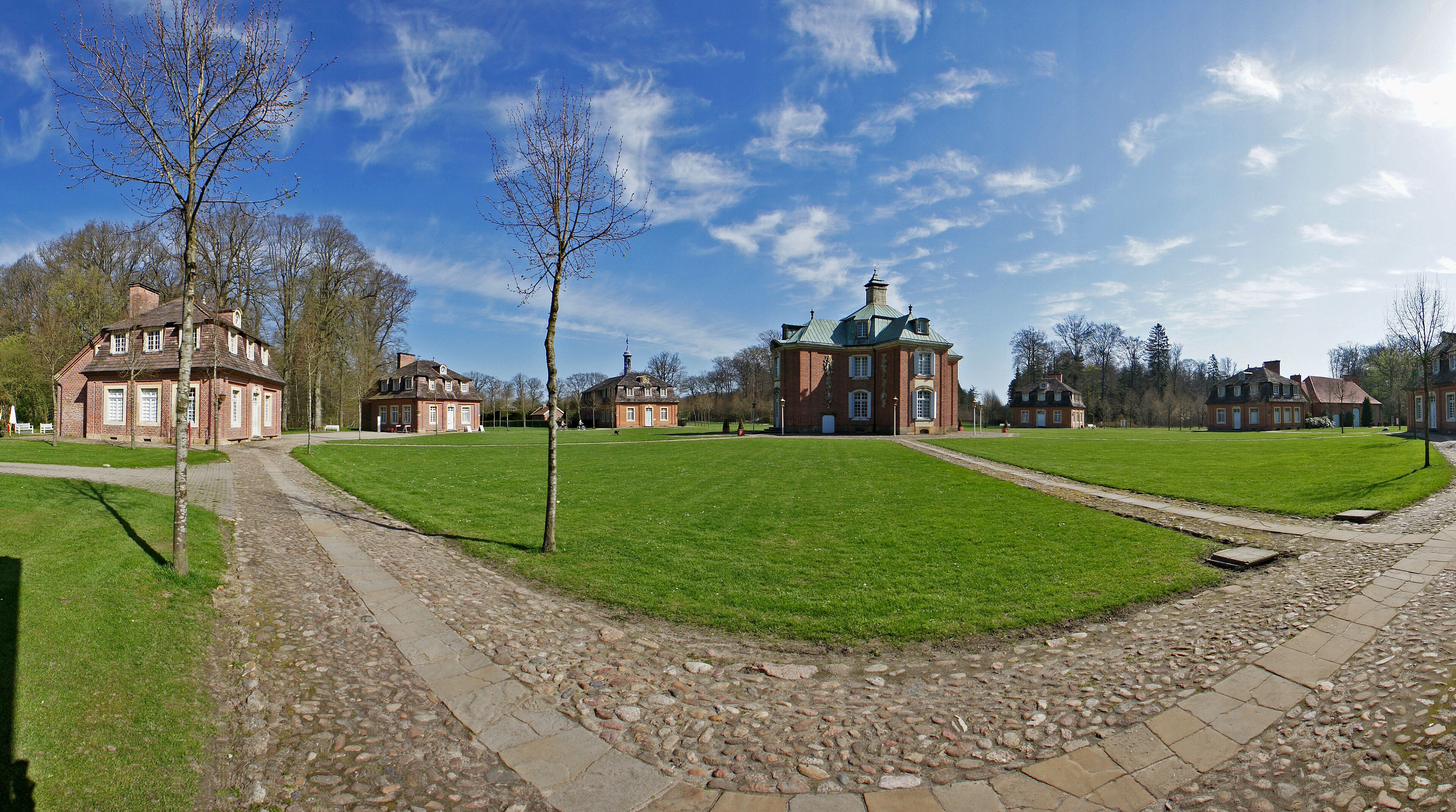A historic building complex with a central lawn, stone pathways, and traditional architecture.