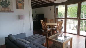 A living room with a sofa, a glass coffee table, and a dining area with a wooden table and chairs.