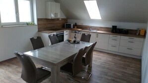 Een moderne keuken met een eettafel, stoelen, een magnetron en een koffiezetapparaat.