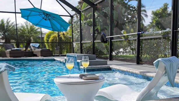 Ein Poolbereich mit Whirlpool, Liegestühlen und einem Getränk.
