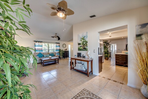 A spacious living room with a ceiling fan, a sofa with cushions, a coffee table, and a dining area with a table and chairs.