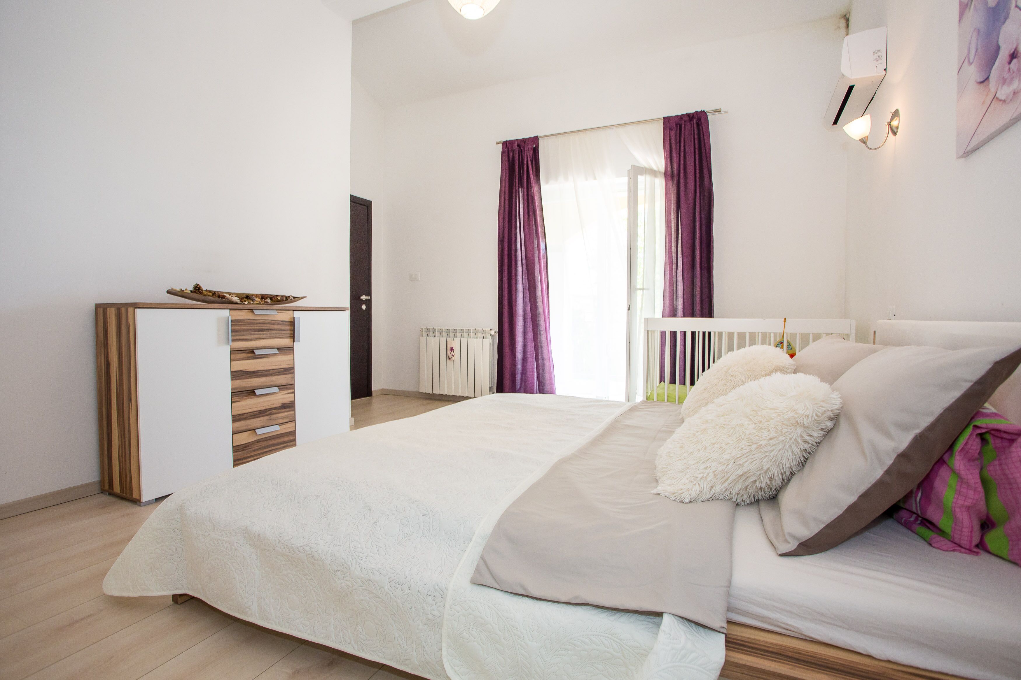 Ein Schlafzimmer mit einem Bett, einem Nachttisch, einem Kleiderschrank und einem Fenster mit Vorhängen.