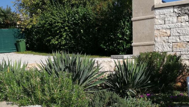 A landscaped garden with a stone wall, steps, and various plants. - Beautiful villa with swimming pool, grill, WIfi, free WiFi (Brecevici, Grintavica)