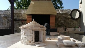 A stone structure resembling a small building with a chimney, surrounded by stone walls and a stone table. - Beautiful villa with swimming pool, grill, WIfi, free WiFi (Brecevici, Grintavica)