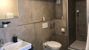 A modern bathroom with a white sink, toilet, and shower. - S-AN Daily Room Stuttgart Center (Claudio2) (Stuttgart Ost)