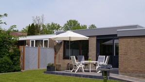 A modern house with a patio area featuring a table, chairs, and a grill. - Chic bungalow (renovated in 2018) directly on the dike to the IJsselmeer / beach (Lemmer)